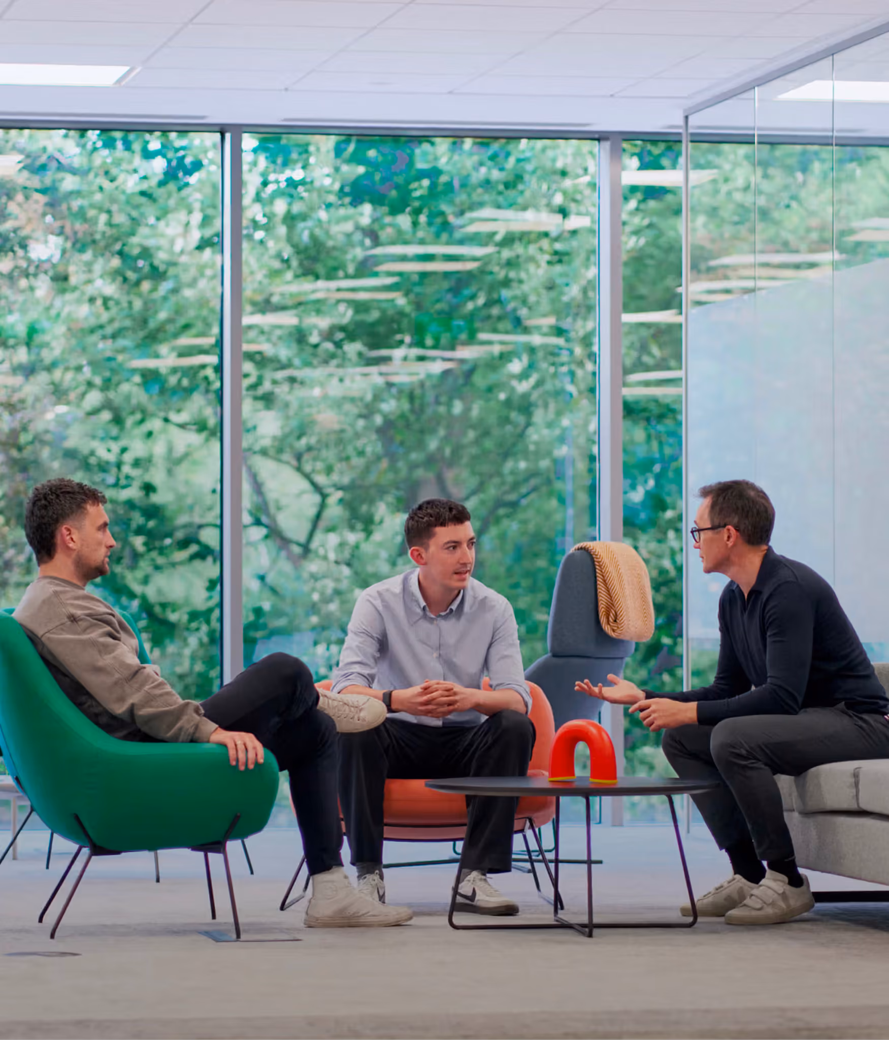 Three colleagues talking in a bright meeting room